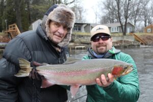 Moser x 2 = Dan, holding colorful male steelhead, along with dad Dave, enjoy an outing on the Muskegon river.